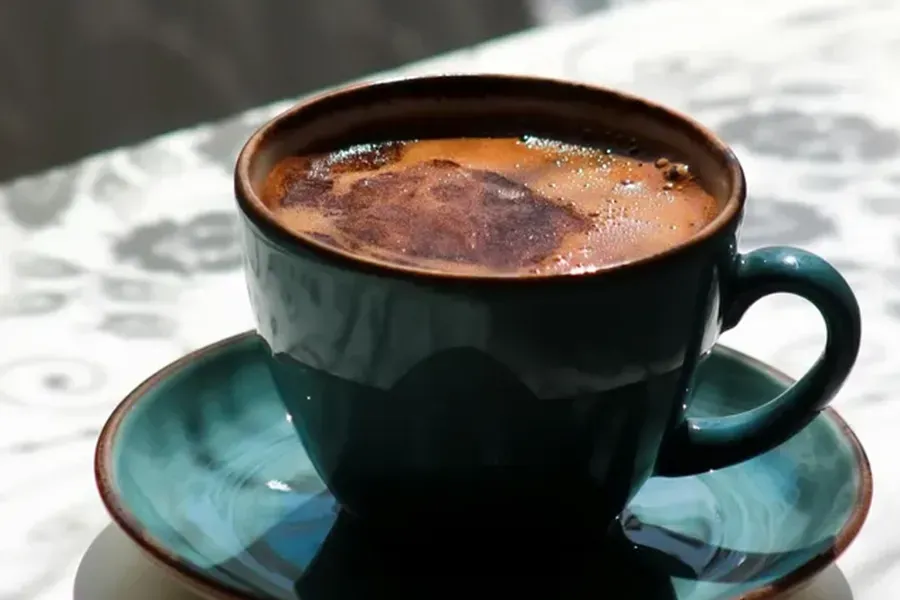 Dark coffee in a teal cup and saucer on a table