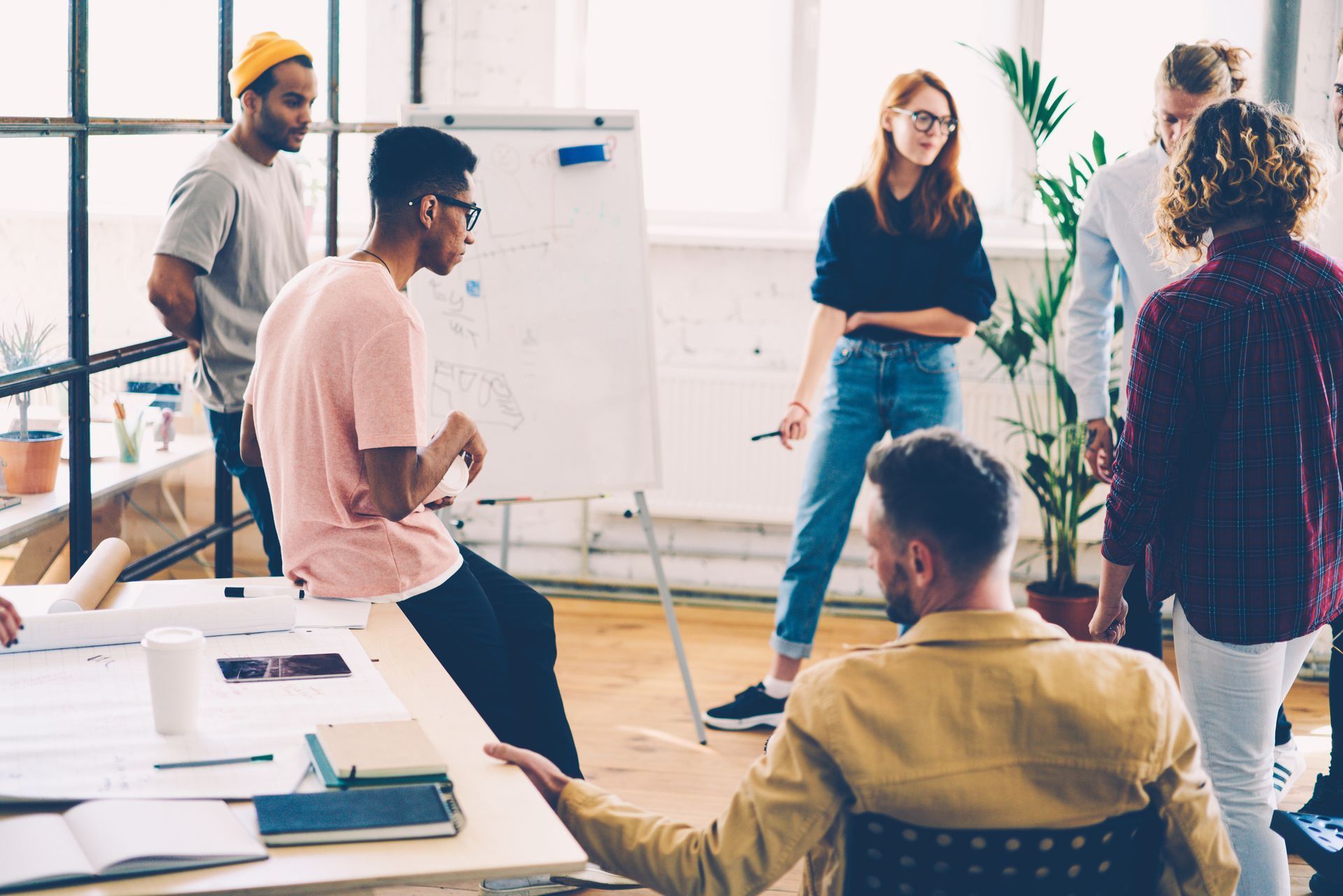 Une équipe de professionnels, discutant autour d'un tableau blanc, dans un environnement de travail moderne et collaboratif.