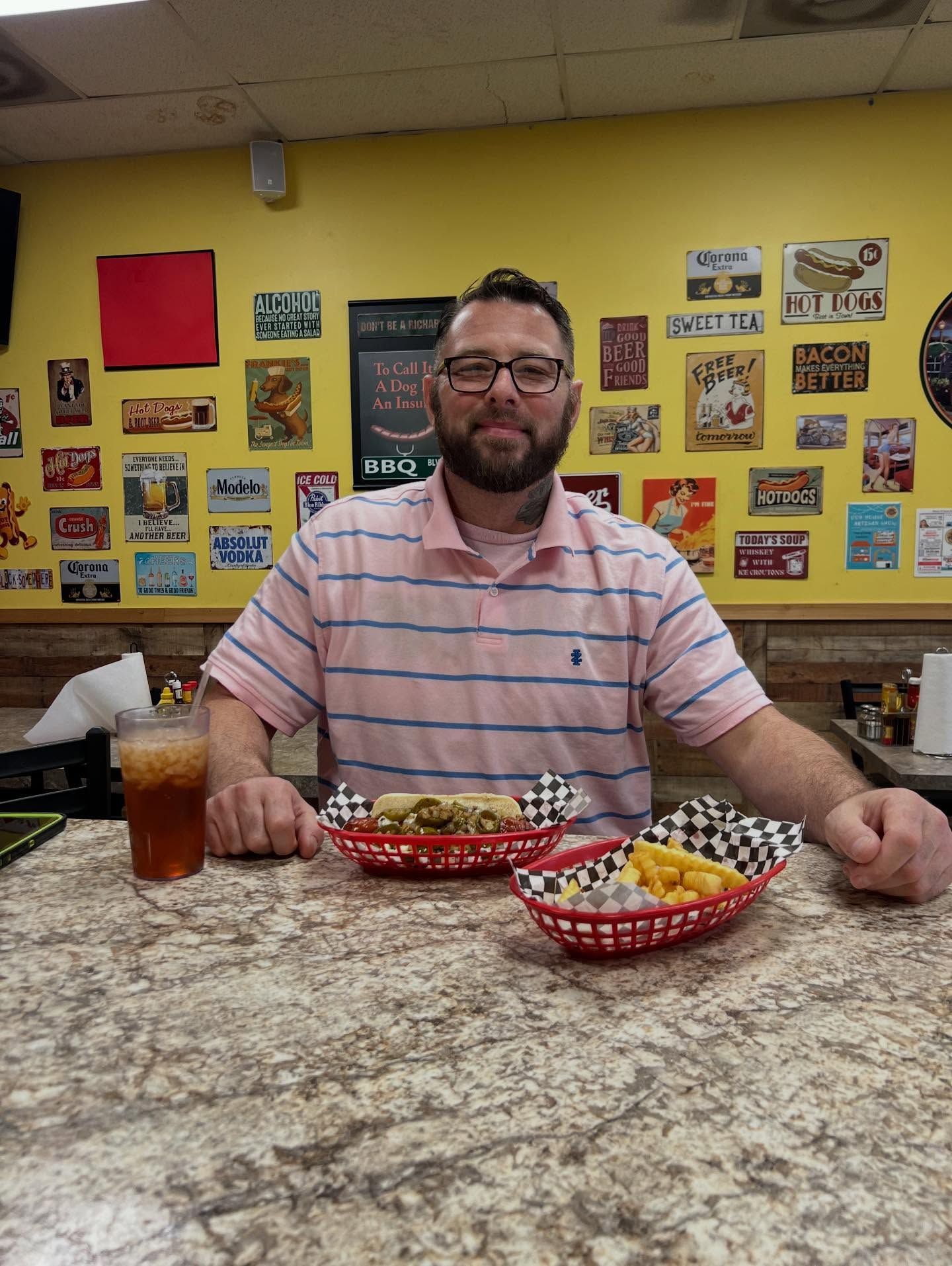 Man seated at a counter with nacho baskets and a drink in a brightly decorated restaurant