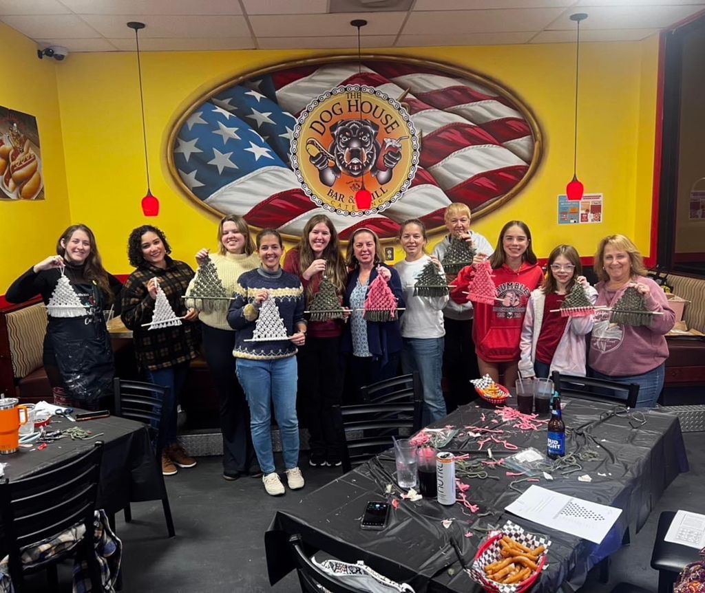 Group of people holding plates in a yellow restaurant decorated with a large American flag mural.