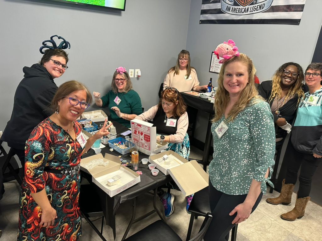Group of people smiling around a table with craft supplies in a bright indoor room