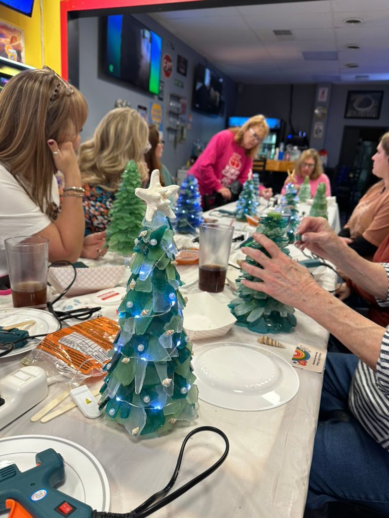 People gathered around a table with small blue-green Christmas tree centerpieces at a holiday meal