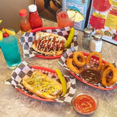 Mexican food spread with tacos, onion rings, sauces, and a blue drink on a checkered tray