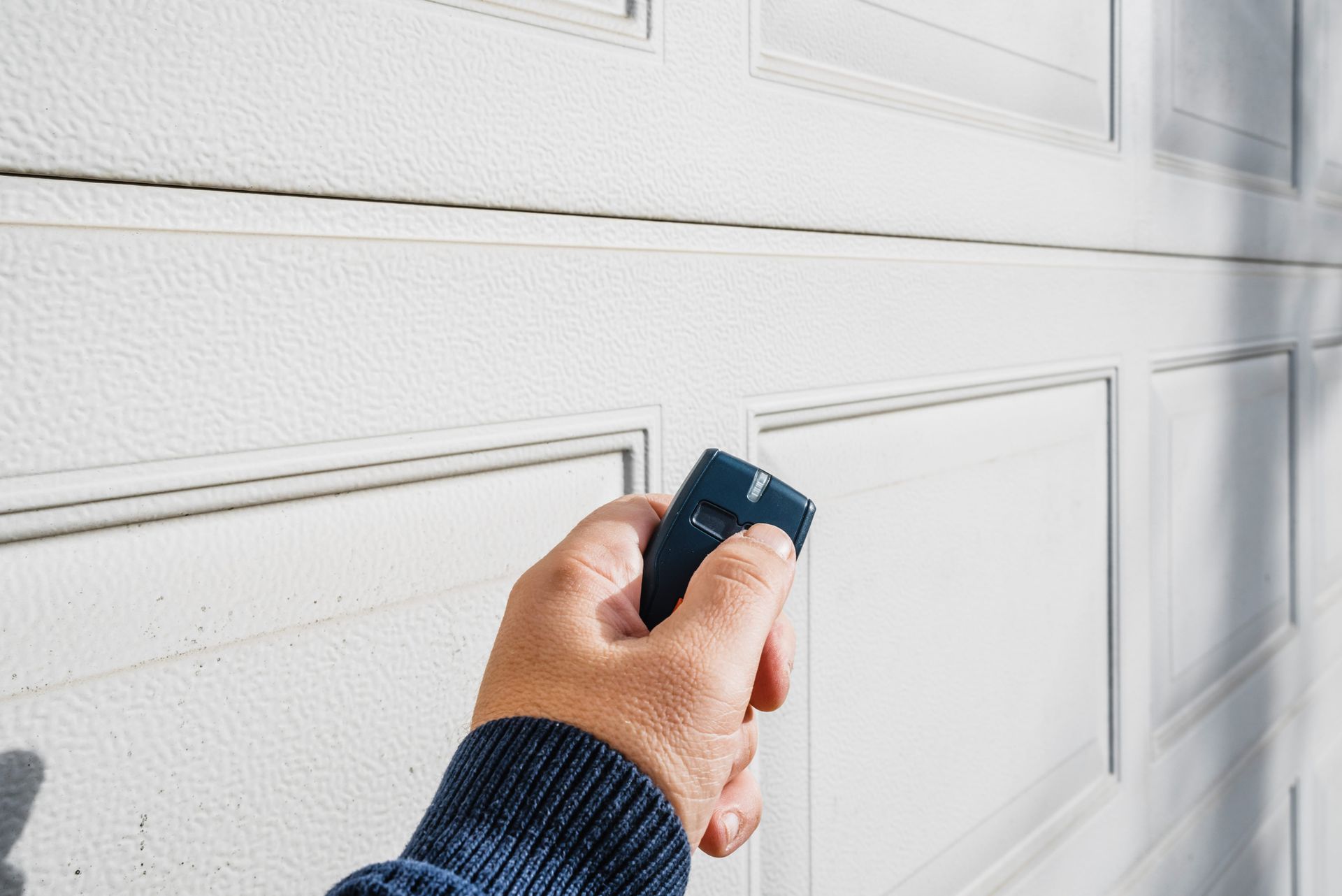 Close-up of hand with garage door, showcasing replacement garage remotes in action