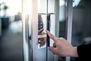 Woman using a keypad lock on a glass door.