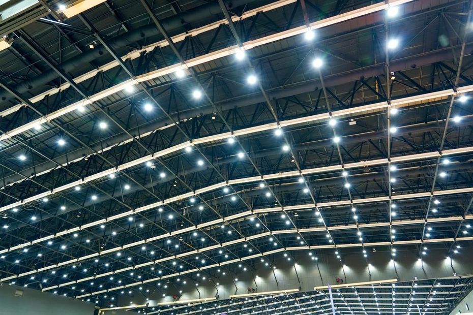 Indoor stadium roof with rows of bright lights and steel beams