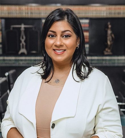 A woman in a white jacket and tan dress is smiling for the camera.