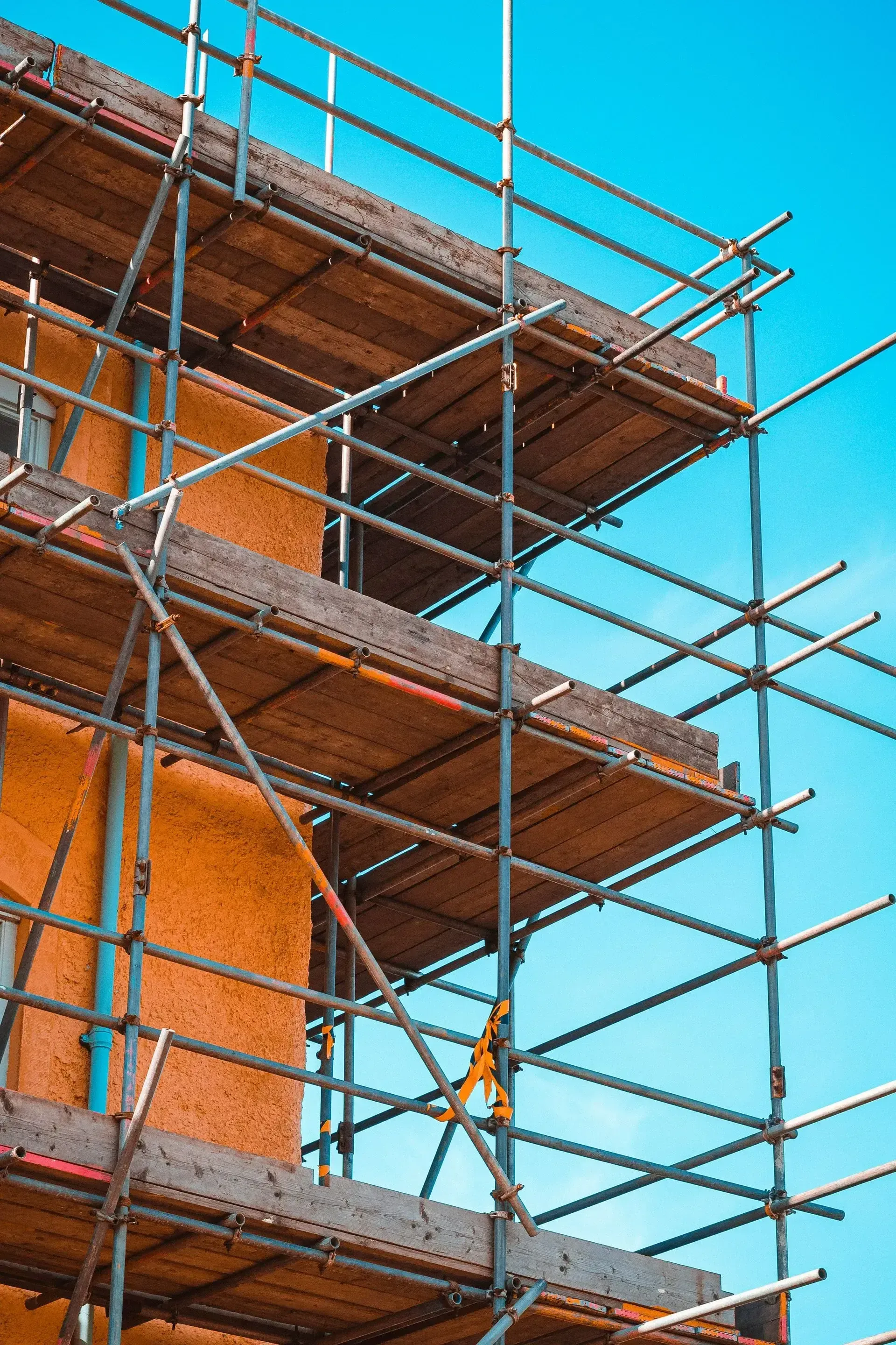 A building is being built with scaffolding and a blue sky in the background.