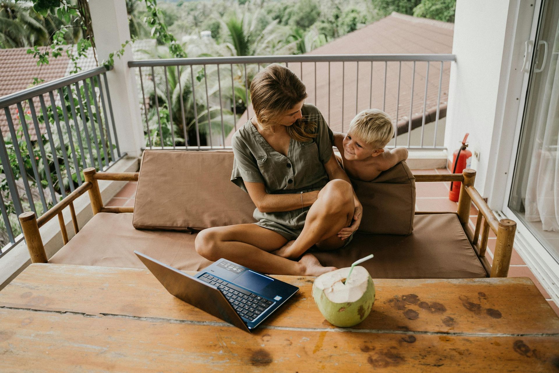 A woman is sitting on a couch with a child and a laptop.