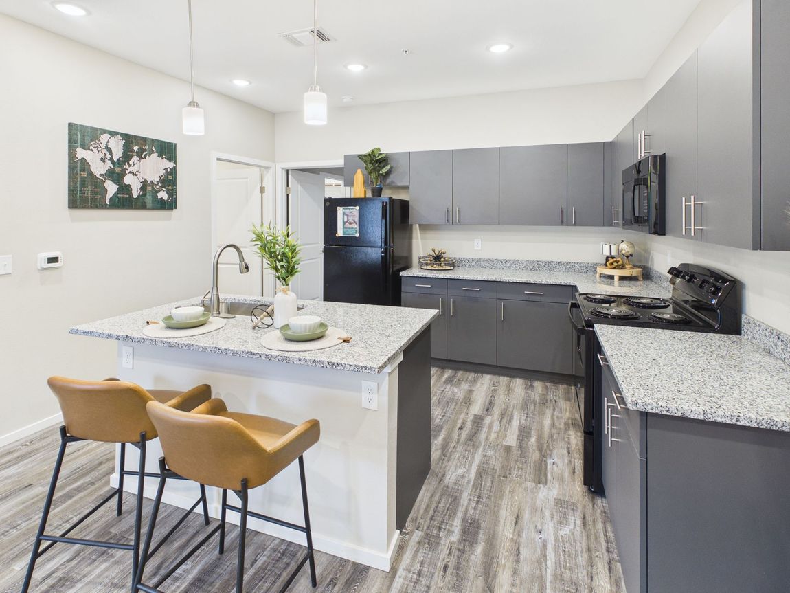 Kitchen with dark brown cabinets, black appliances, and a jute rug.