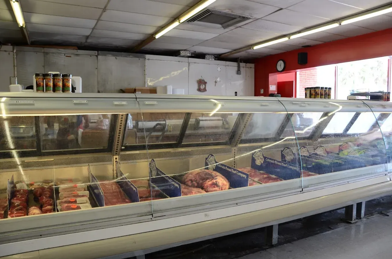 Butcher shop display case with assorted meats in a long refrigerated counter