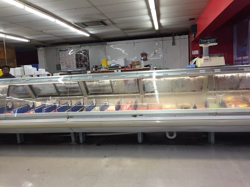 Empty restaurant counter with a glass display case and rows of food trays under bright lights