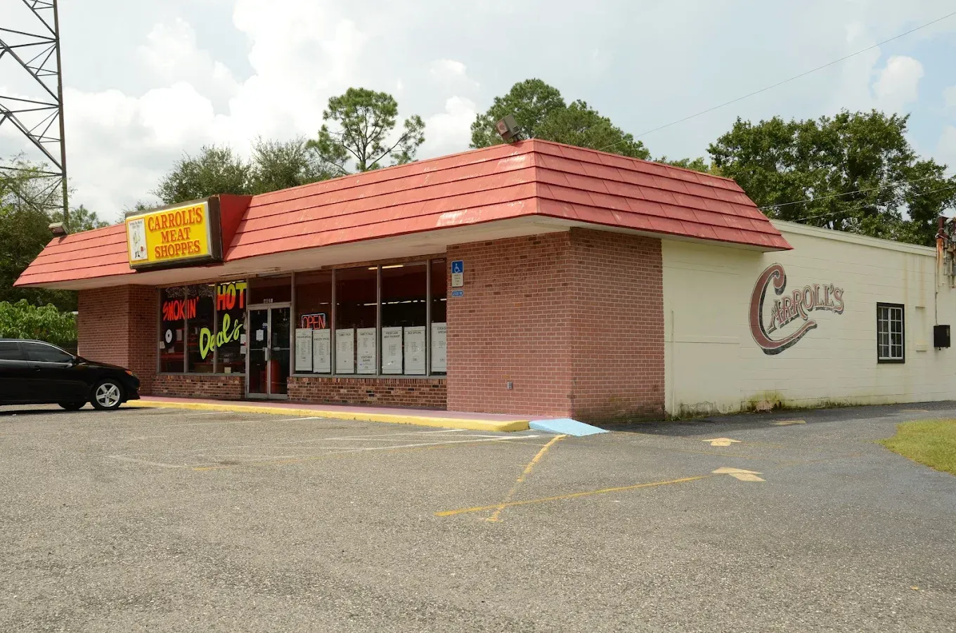 Small brick restaurant with red roof and a parking lot, viewed from the front corner.