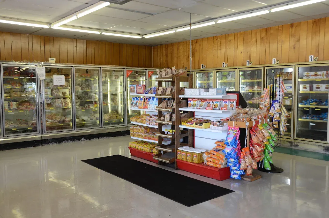Convenience store interior with refrigerated aisles, central snack display, and polished floor