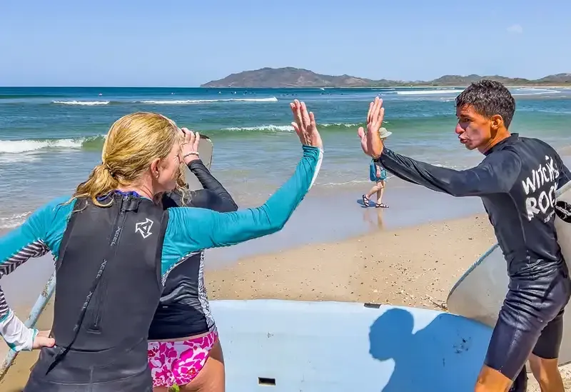 A man and a woman are giving each other a high five on the beach.