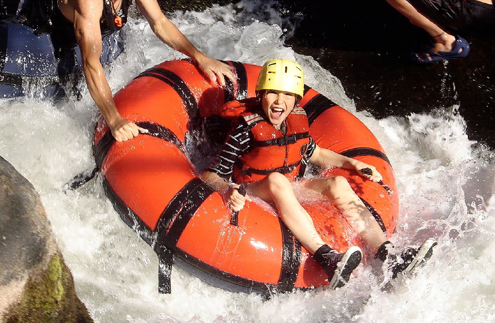 A person wearing a yellow helmet is floating down a river in a raft.