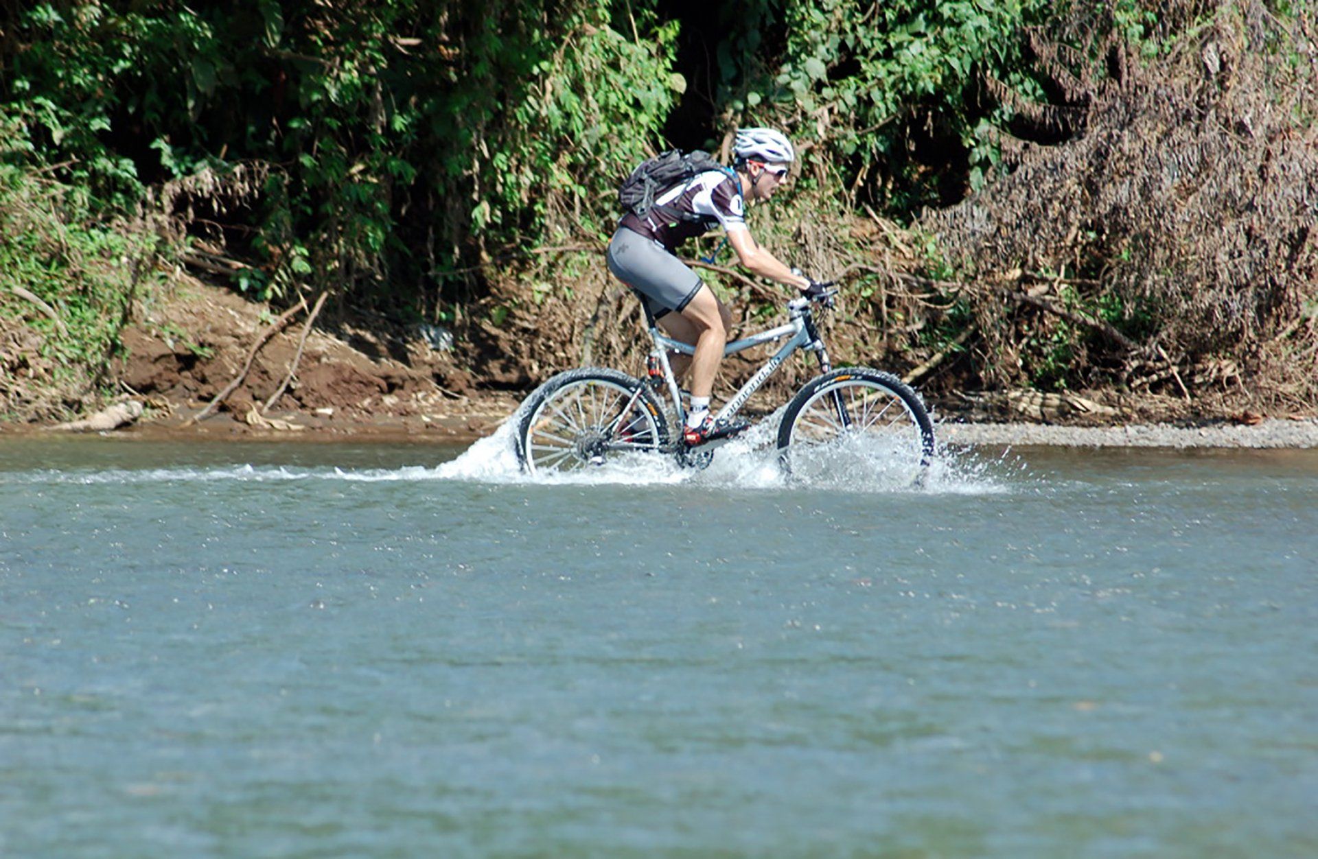 A man is riding a bike through a river