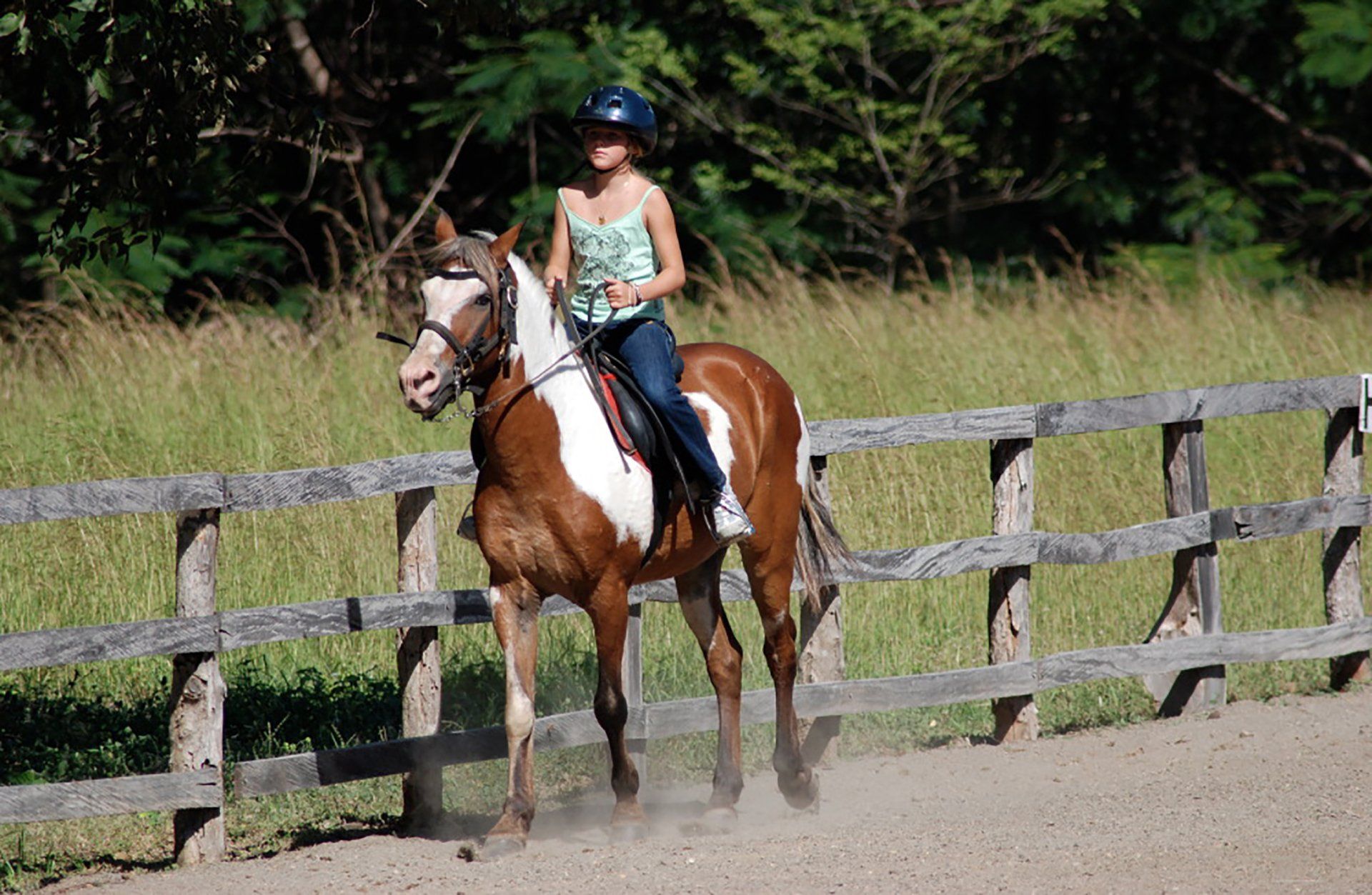 A woman is riding a brown and white horse in a field