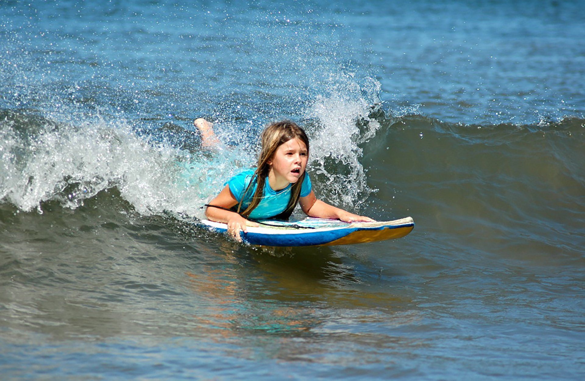 A young girl is riding a wave on a surfboard in the ocean.
