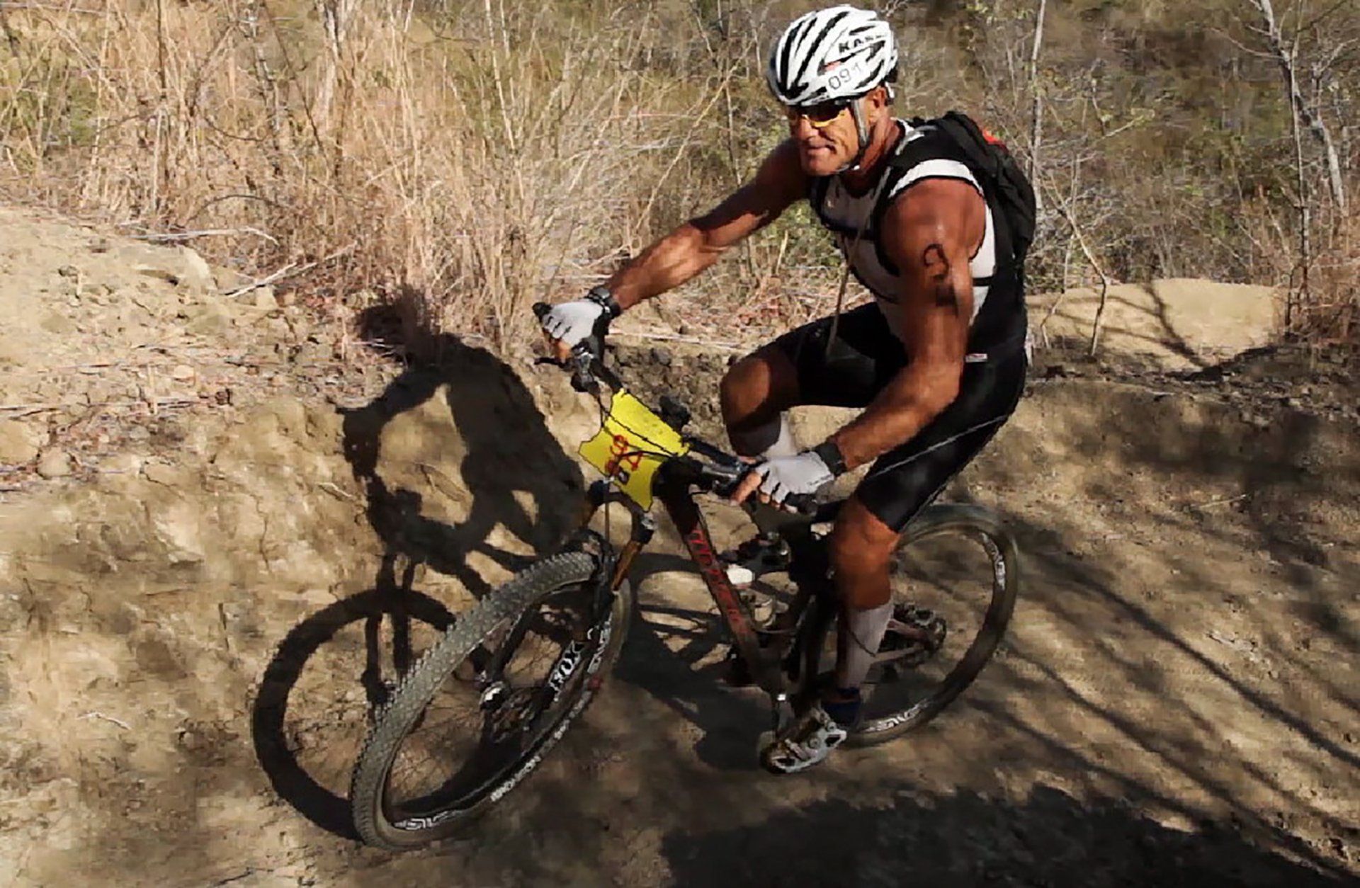 A man wearing a helmet is riding a bike on a dirt road