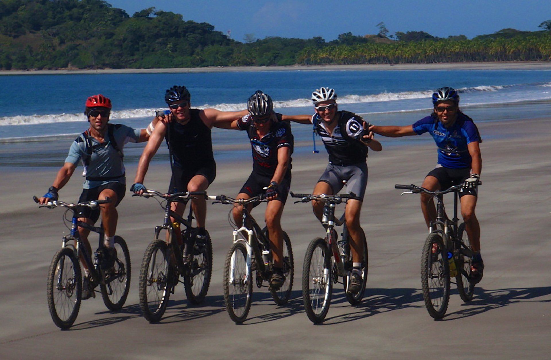 A group of people are riding bikes on the beach