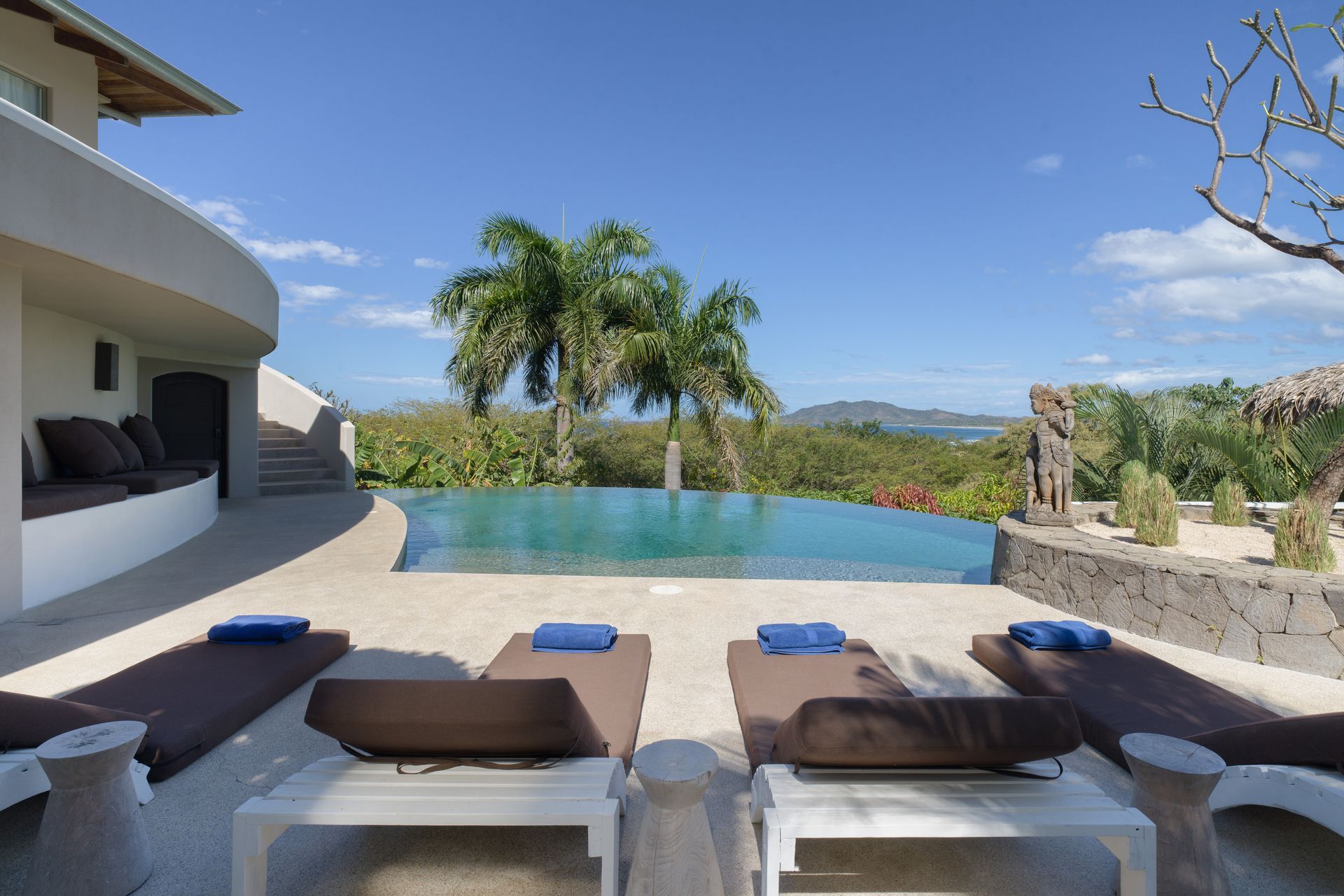 A large patio with a table and chairs and a thatched roof.