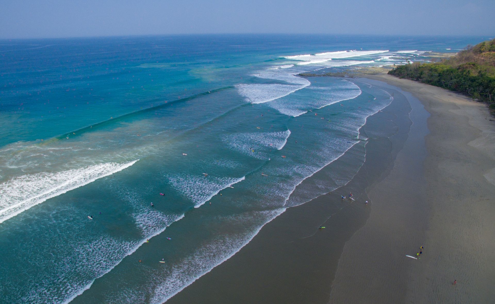 An aerial view of a beach with waves crashing on the shore.