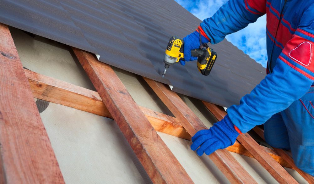 A Man Is Installing A Roof With A Drill — Glenroofing Pty Ltd In Kempsey, NSW