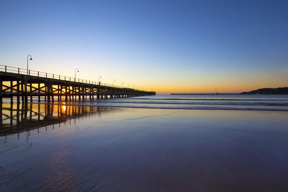 A Pier Overlooking A Body Of Water At Sunset — Glenroofing Pty Ltd In Coffs Harbour, NSW