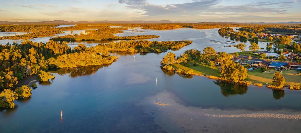 An Aerial View Of A Large Lake Surrounded By Trees And Houses — Glenroofing Pty Ltd In Forster, NSW