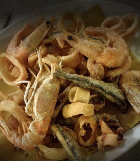 Ciotola di frutti di mare e verdure miste fritte, tra cui gamberi e anelli di cipolla.
