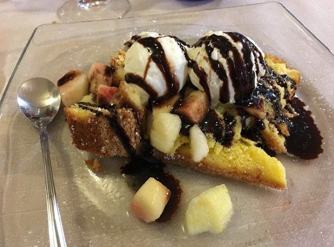 Piatto da dessert con gelato, frutta, salsa al cioccolato e cucchiaio su un vassoio