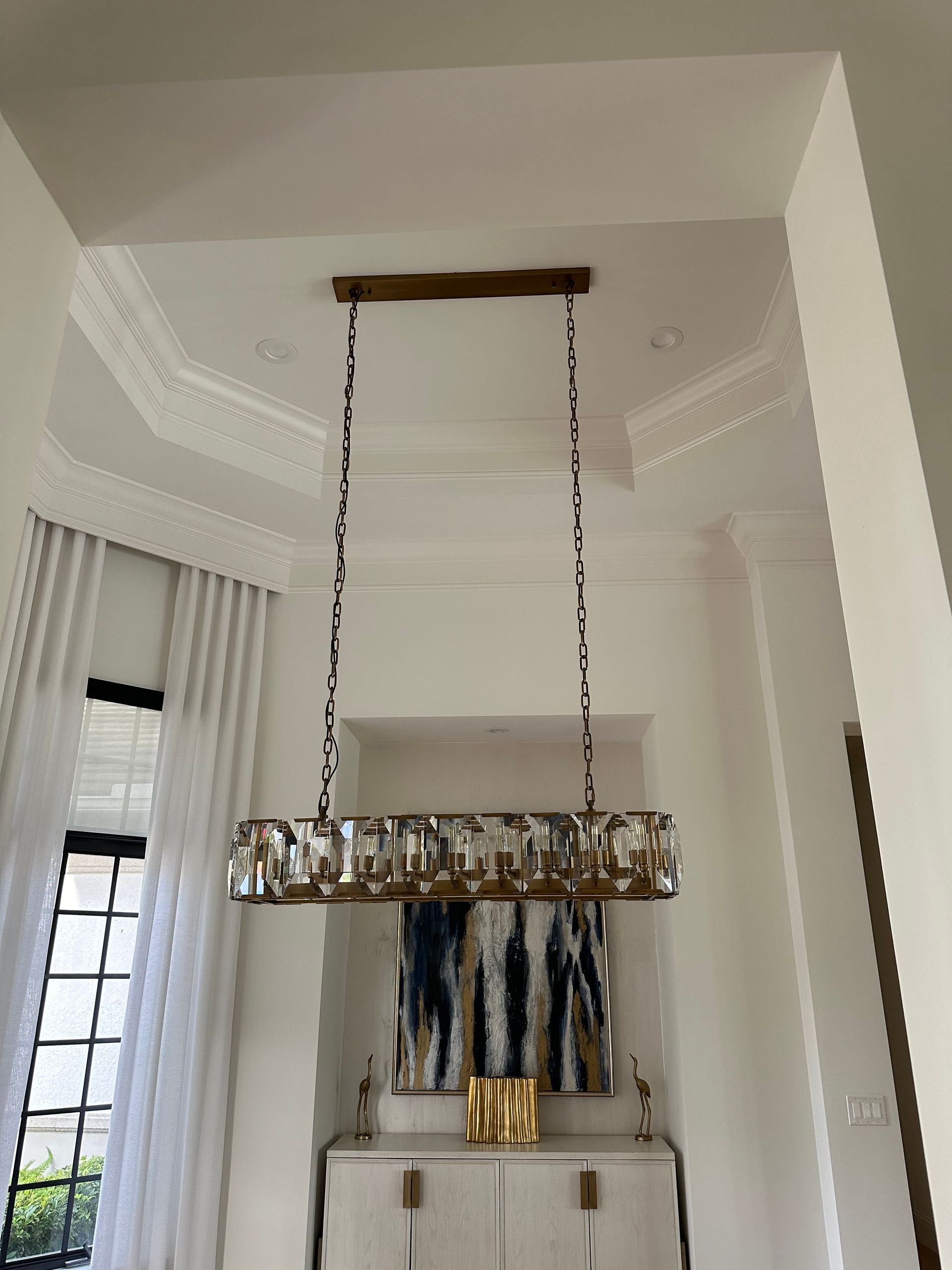 A chandelier is hanging from the ceiling in a dining room.