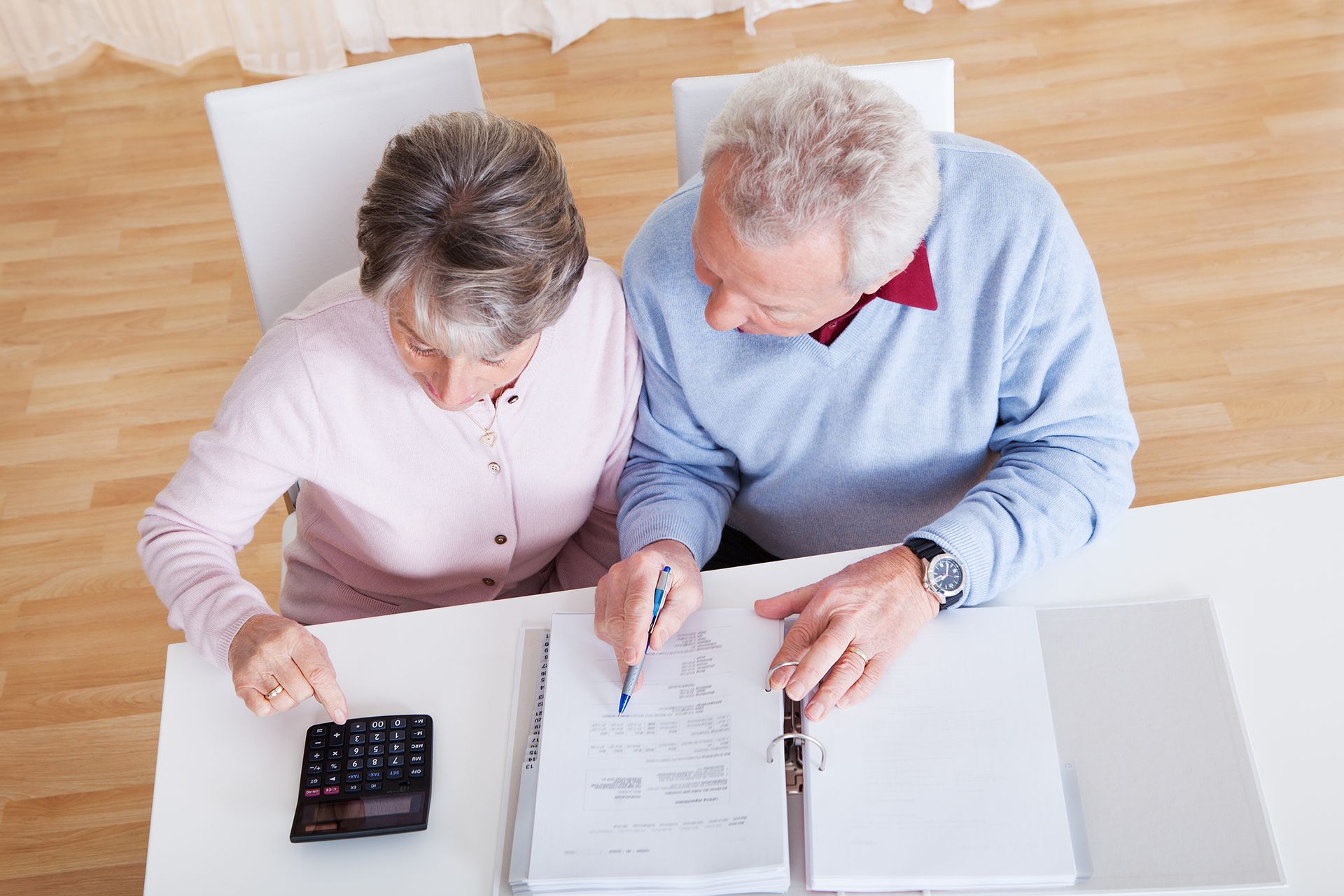 A man and a woman are sitting at a table with a calculator.