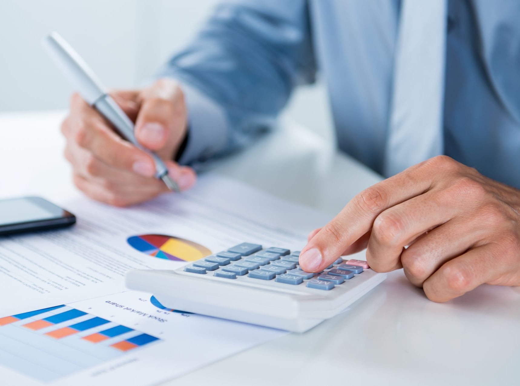 A man is using a calculator and writing on a piece of paper.