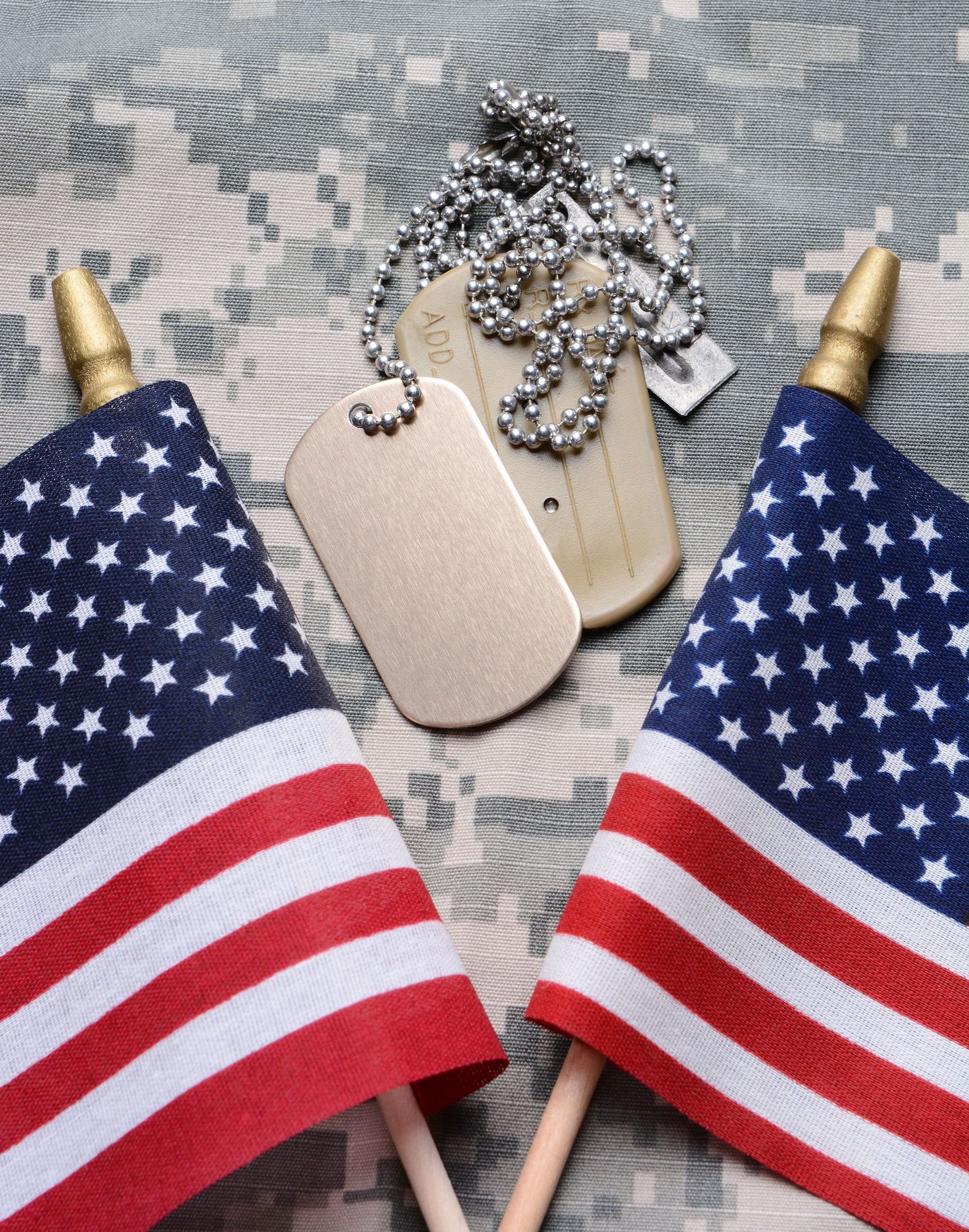 Two american flags and a dog tag on a camouflage background