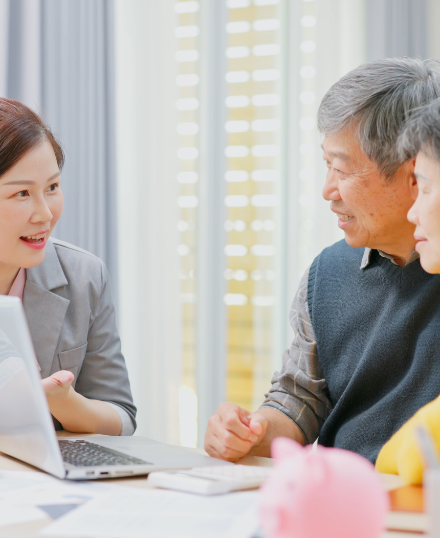 A man and a woman are sitting at a table looking at a laptop