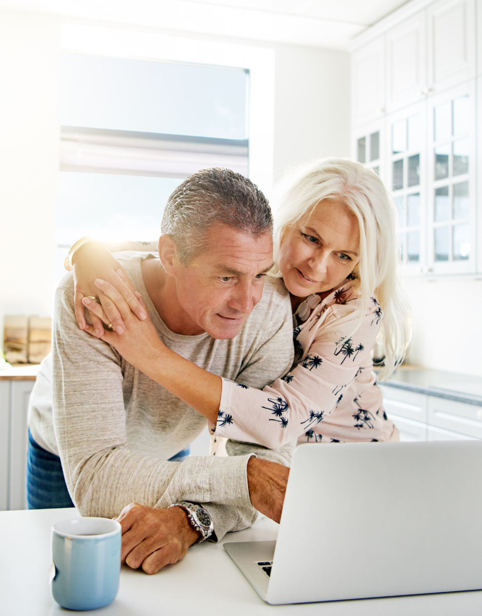 A man and a woman are looking at a laptop computer.