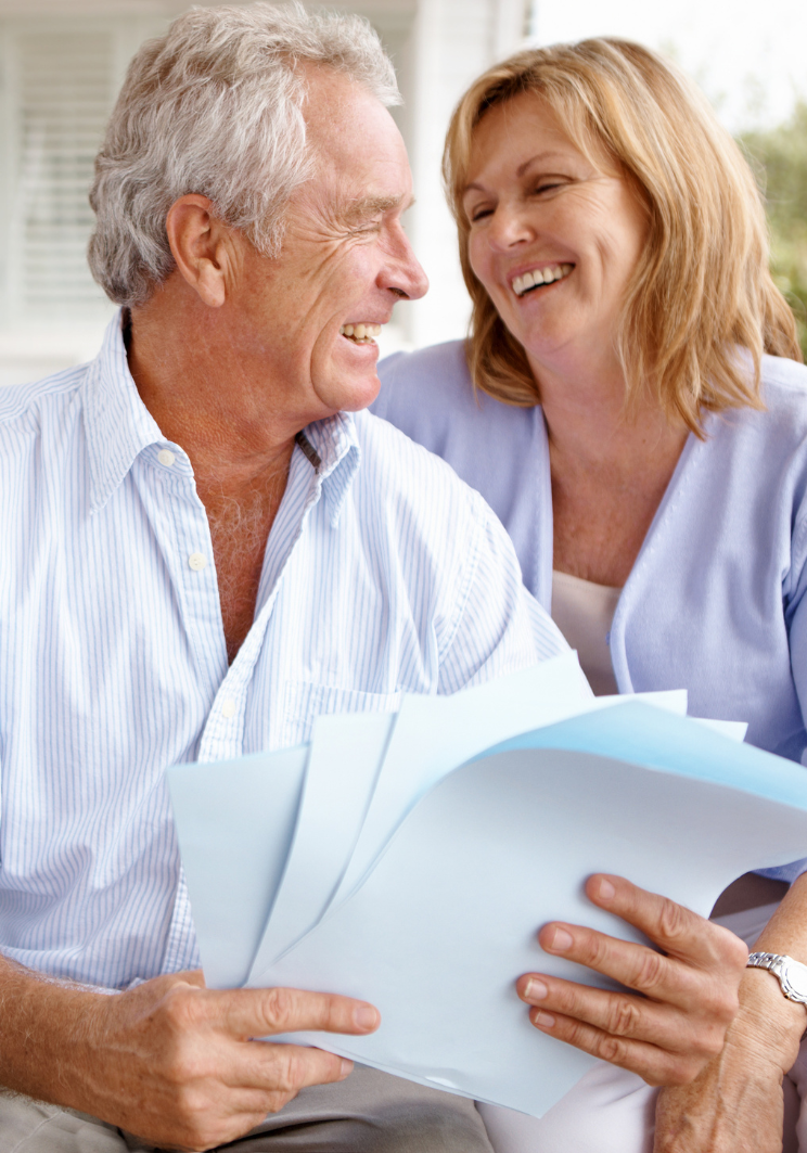 A man and a woman are sitting on a couch looking at papers.