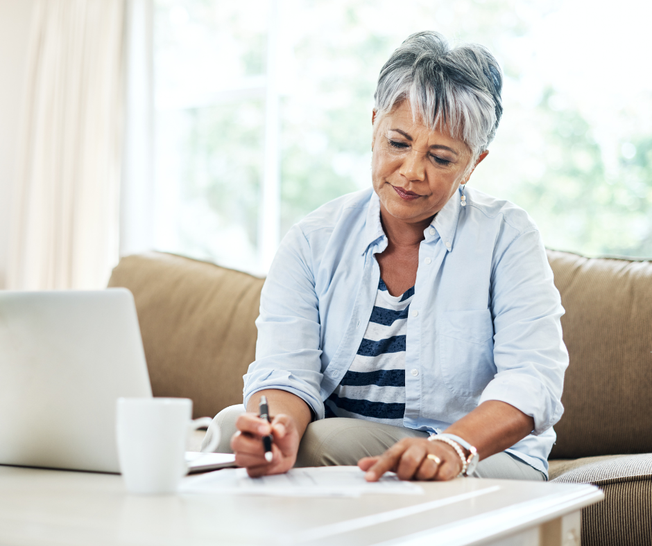 An older woman is sitting on a couch using a laptop computer.