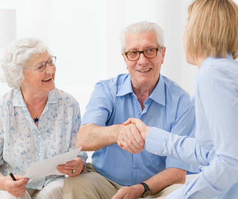 An elderly couple is shaking hands with a woman.