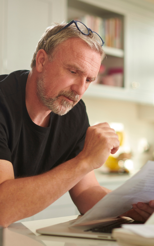 A man is sitting at a table looking at a piece of paper.