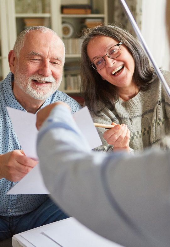 A man and a woman are laughing while looking at a piece of paper.