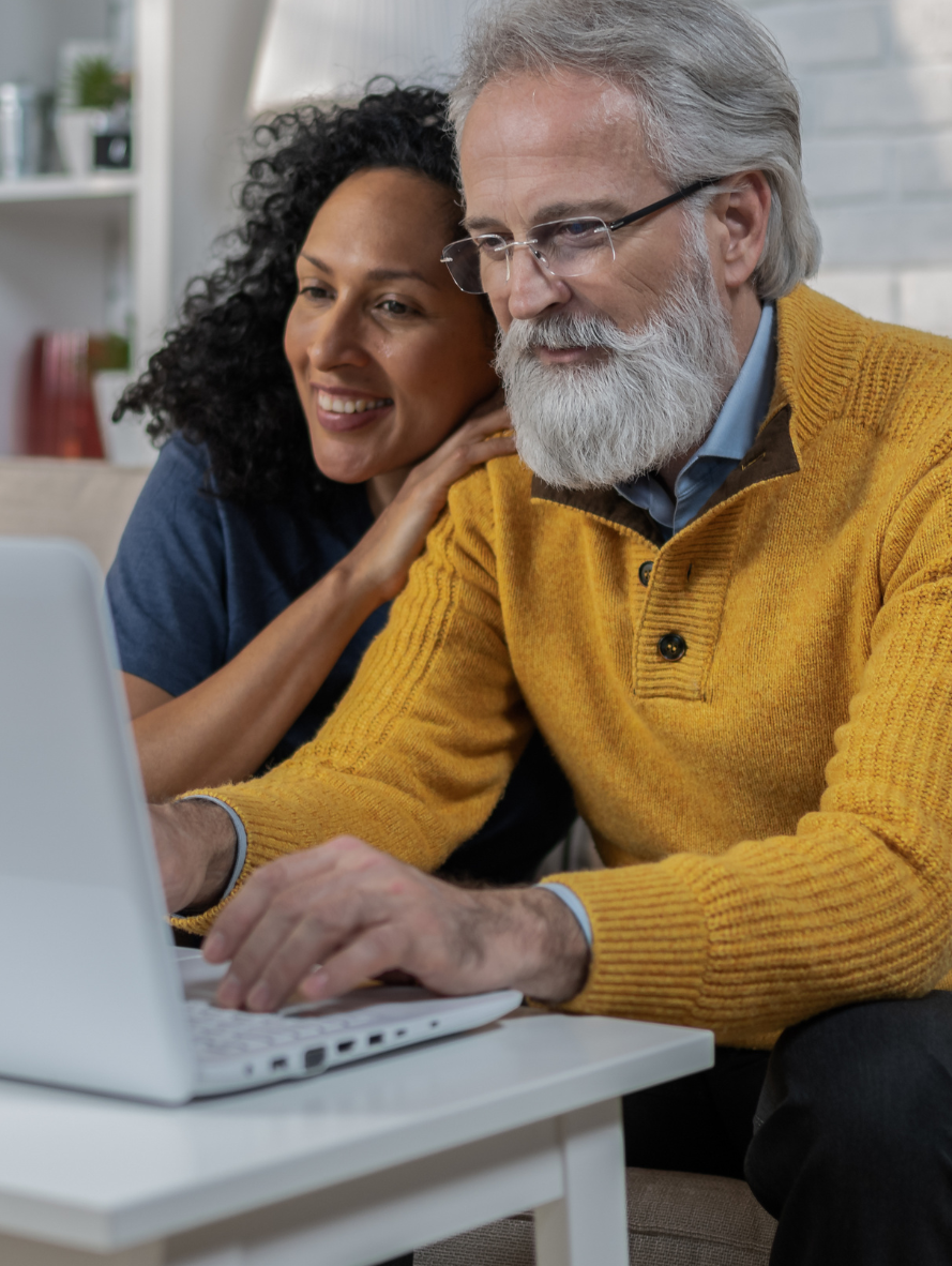 A man and a woman are looking at a laptop computer.