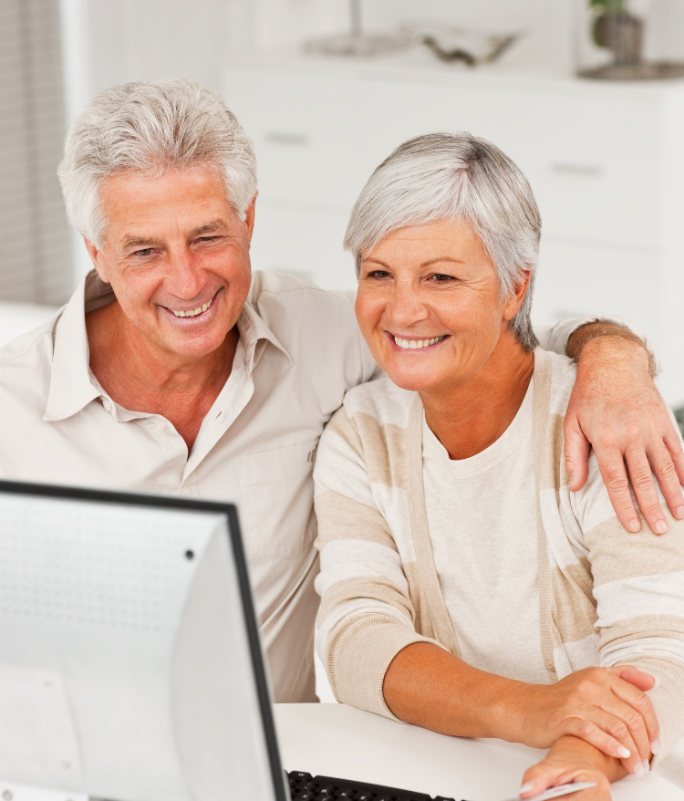 A man and woman are smiling while looking at a computer screen