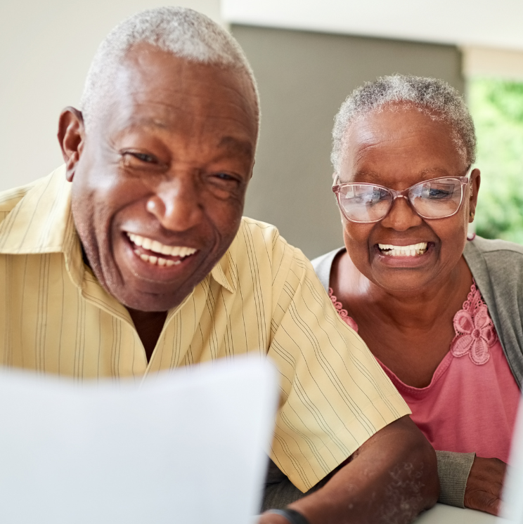 A man and woman are smiling while looking at a laptop