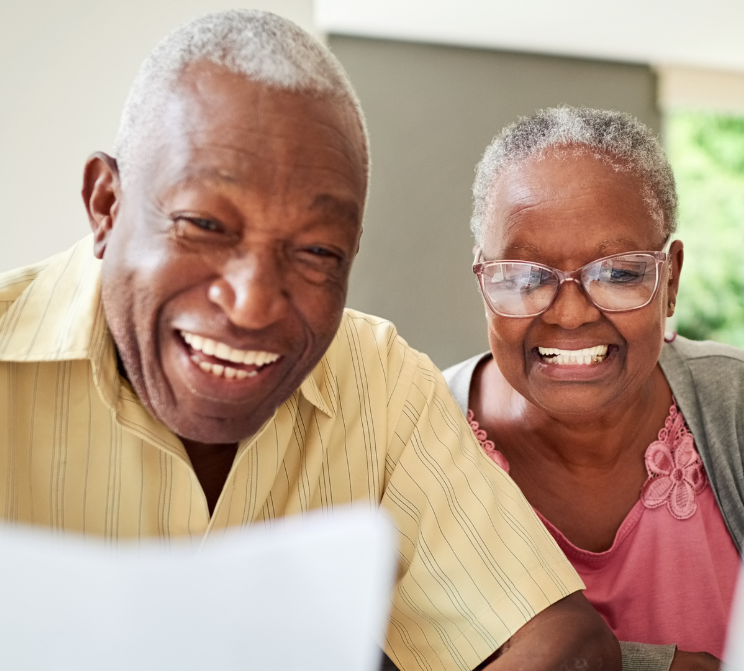 A man and a woman are smiling while looking at a laptop.