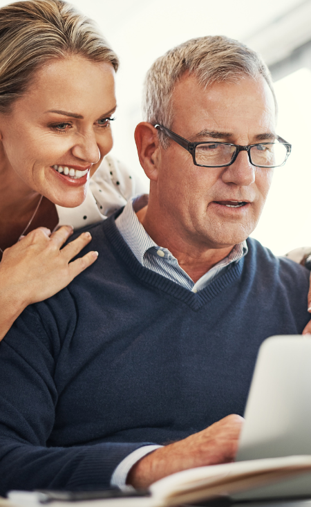 A man and a woman are looking at a laptop together.