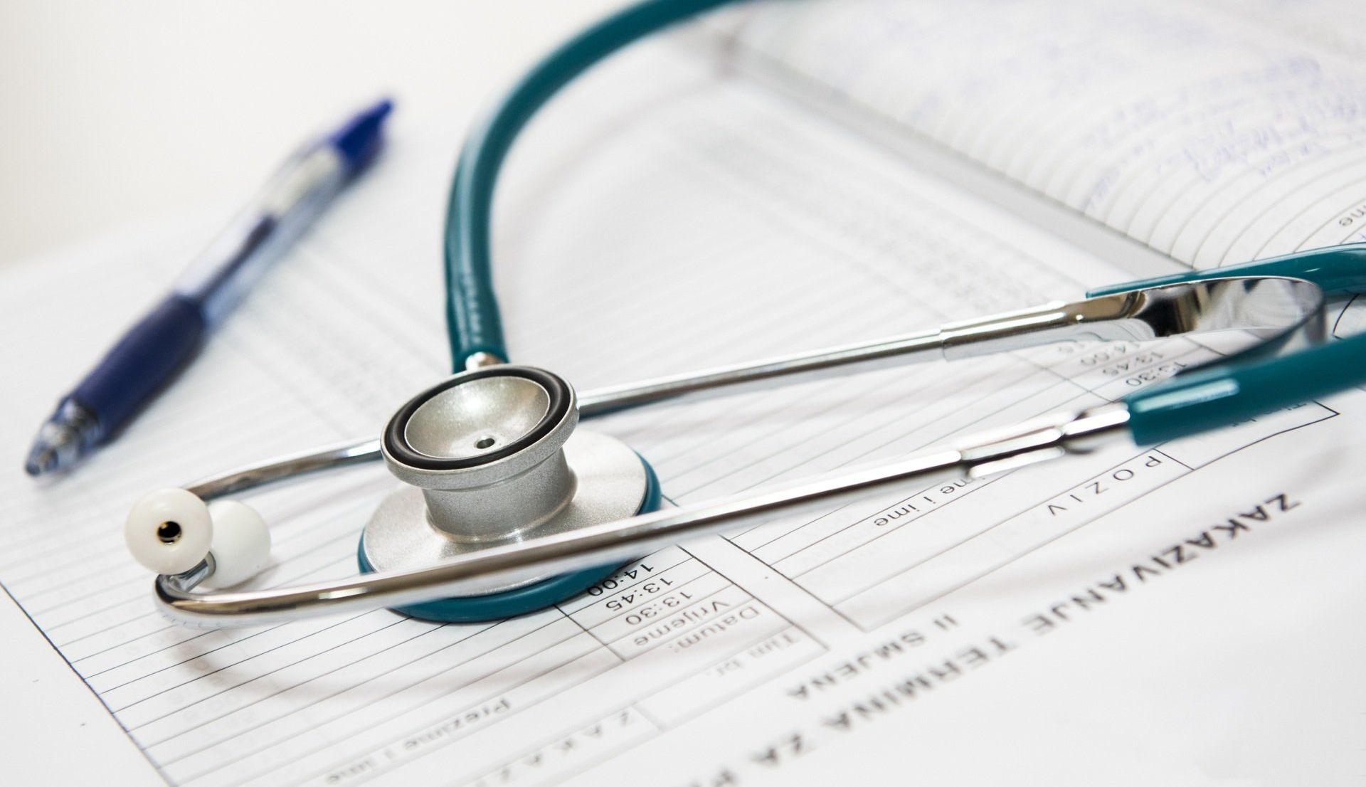 A stethoscope is sitting on top of a piece of paper next to a pen.