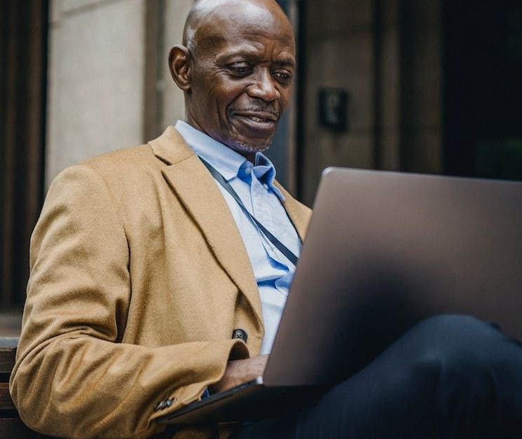 A man in a suit is sitting in front of a laptop computer.
